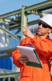 Two engineers in orange suits and hard hats reviewing work 